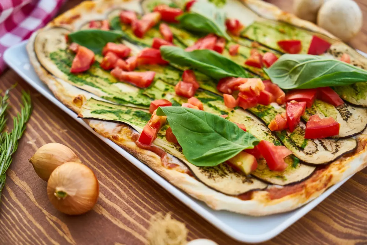 Hemmagjord pizza med tunn botten, färska tomater, basilika och grönsaker